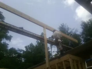 Carpenter setting a ridge beam over a new addition frame — Ice Dam Removal by Roofing Brothers in Browning