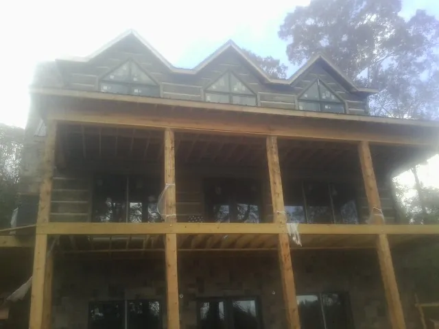 Dormers and porch framing on a large log home under construction — Roof Coating work by our crew in Browning