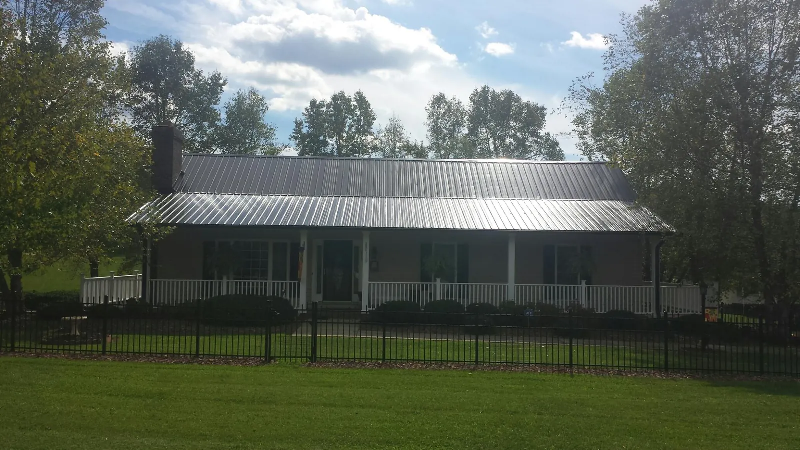 Gray metal roof on a brick ranch with a full width front porch — Gutter Guard Installation work by our crew in Browning