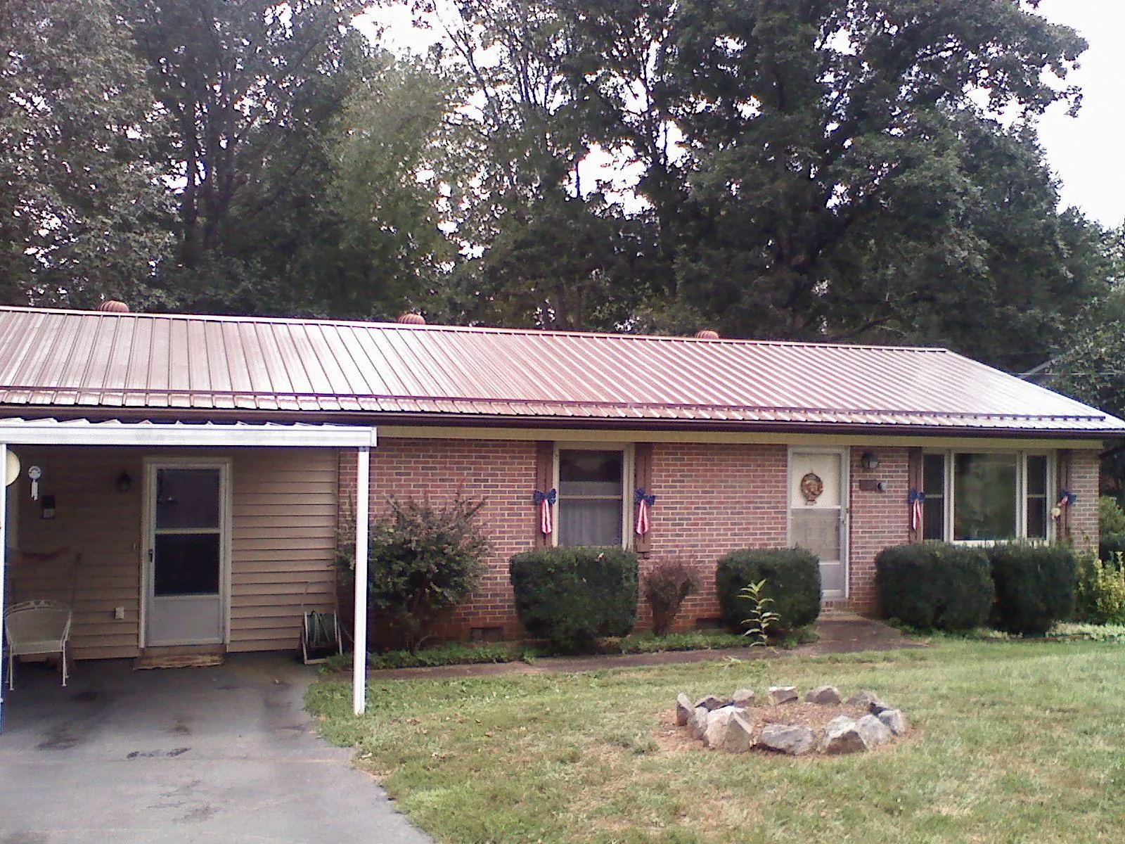 Bronze metal roof and carport on a brick ranch home — Roof Repair work by our crew in Browning